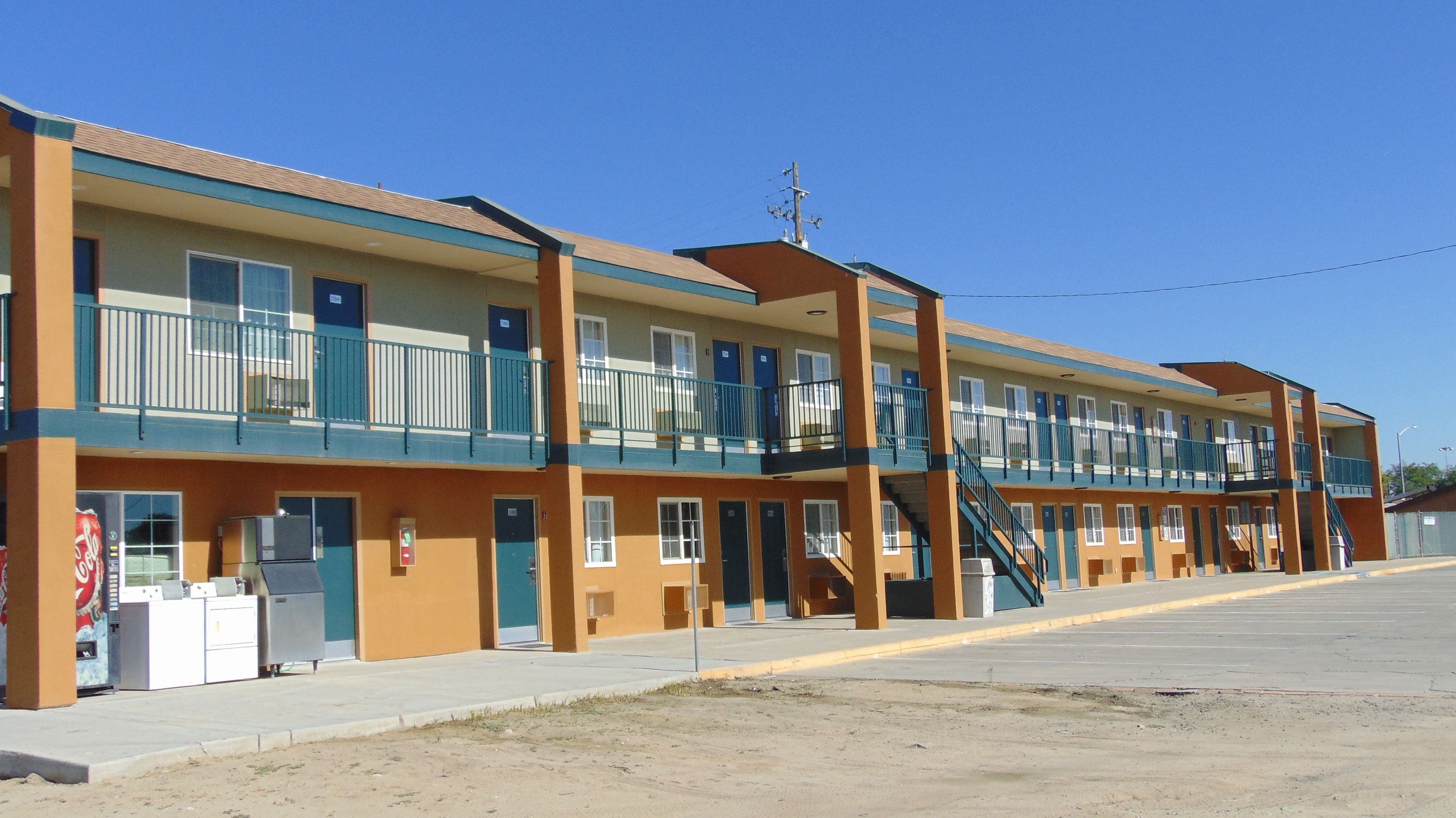 A motel with multiple floors, exterior stairs, and a Coca-Cola vending machine.
