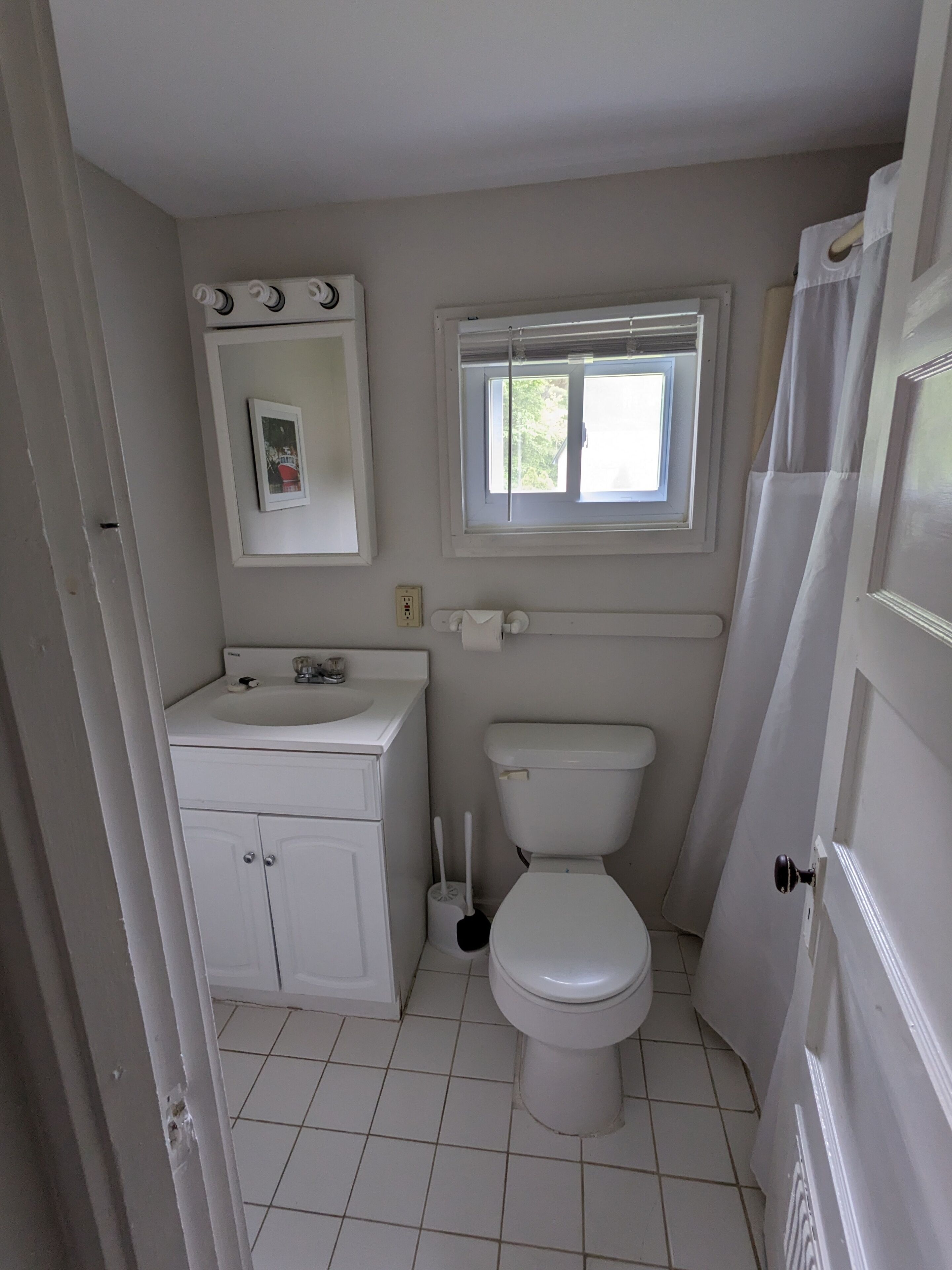 Une petite salle de bain propre, équipée de toilettes, d’un lavabo et d’une fenêtre.