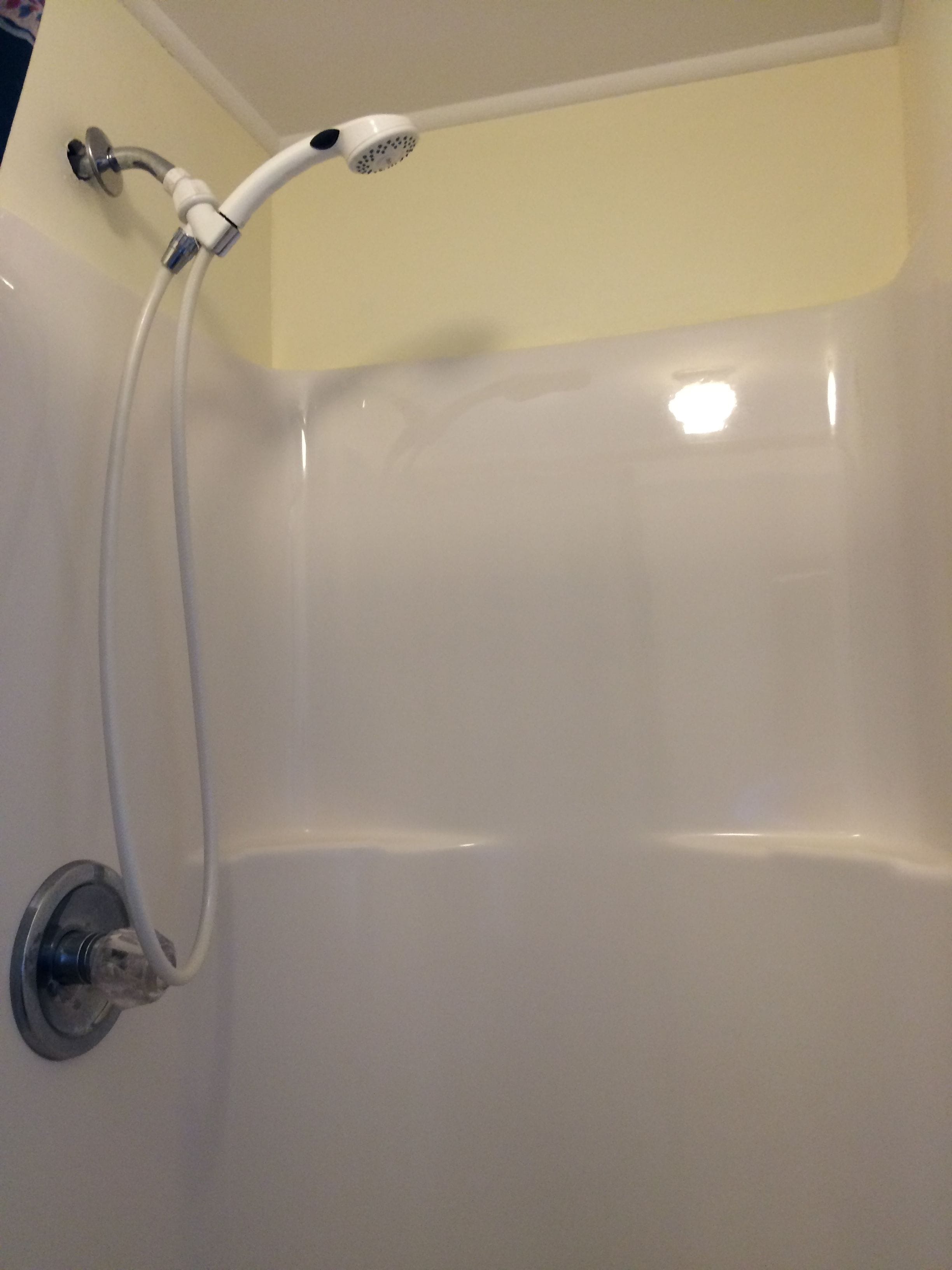 A white bathtub with a showerhead and hose.