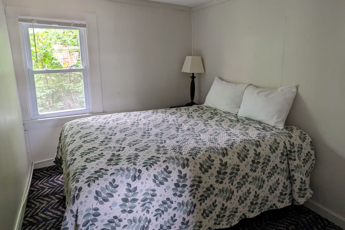 Quarto com uma cama, uma janela e um abajur.