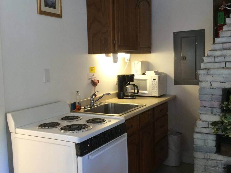 Una cucina compatta con un fornello bianco, lavello e mobili in legno.