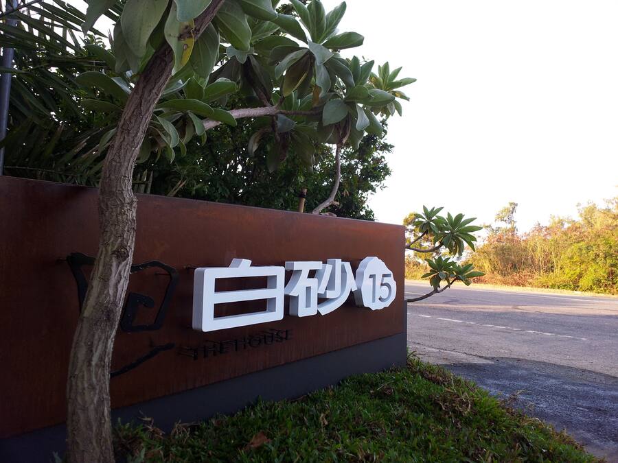 A sign with the text "THE HOUSE" and a tree in front of it.