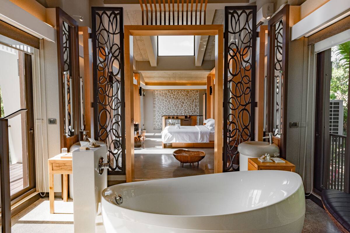 A modern bathroom with a large bathtub, a wooden vanity, and a separate shower area.