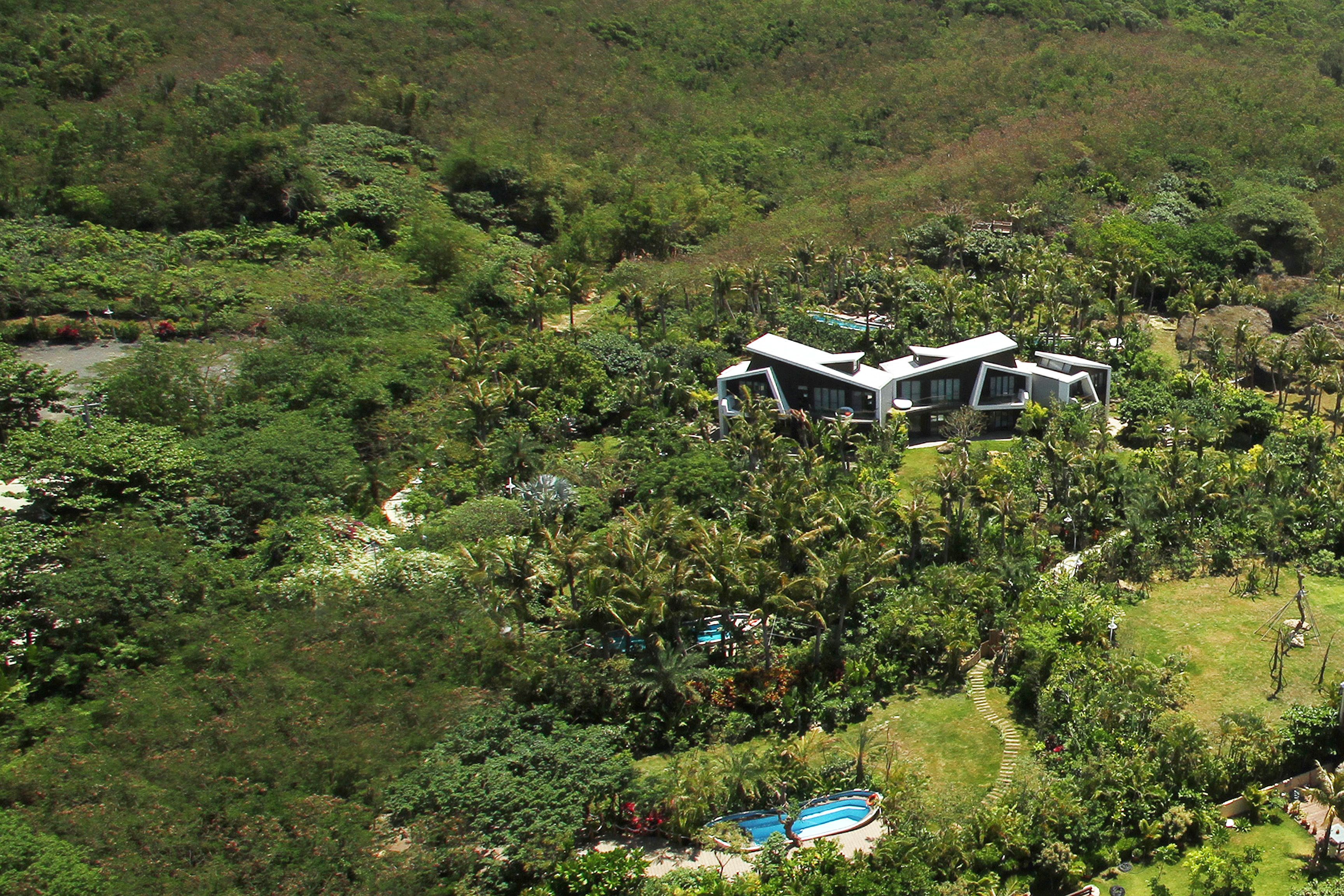 Una casa moderna rodeada de exuberante vegetación, con una piscina y una vista despejada del paisaje circundante.