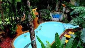 A circular pool surrounded by lush greenery and tropical plants. - Khao Sok Tree House (Phanom)