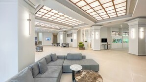 Un vestíbulo amplio con un sofá modular, una mesa de centro redonda y un televisor montado en la pared.