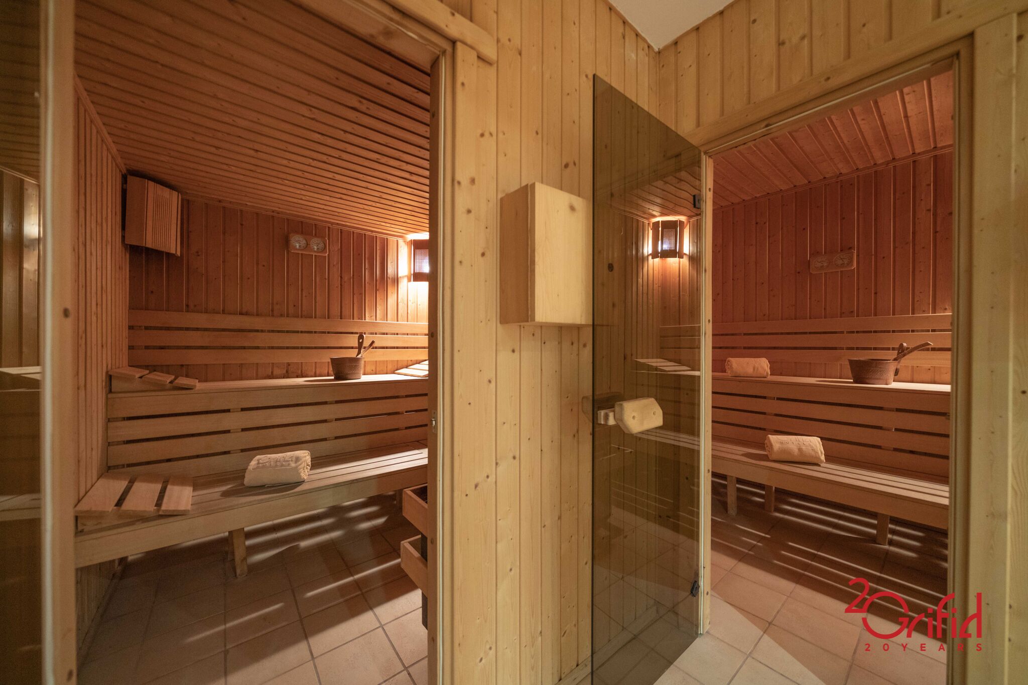 A sauna room with wooden benches and benches, a glass door, and a towel rack.