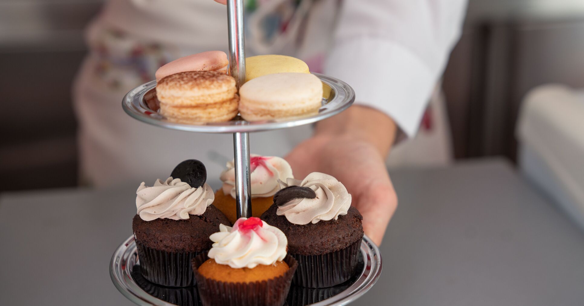A tiered dessert stand with cupcakes and macarons.