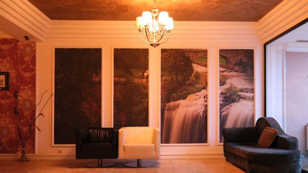 Un salón amplio con una lámpara moderna, dos sofás y grandes cuadros de paisajes en las paredes.
