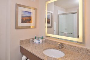 A bathroom with a granite countertop, a sink, a framed picture, and a mirror. - Holiday Inn Express & Suites Dearborn SW - Detroit Area by IHG (Dearborn)