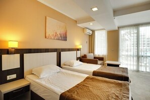 A hotel room with two beds, a desk, a chair, and a large window with curtains. - DIT Evrika Beach Club Hotel (Sunny Beach)