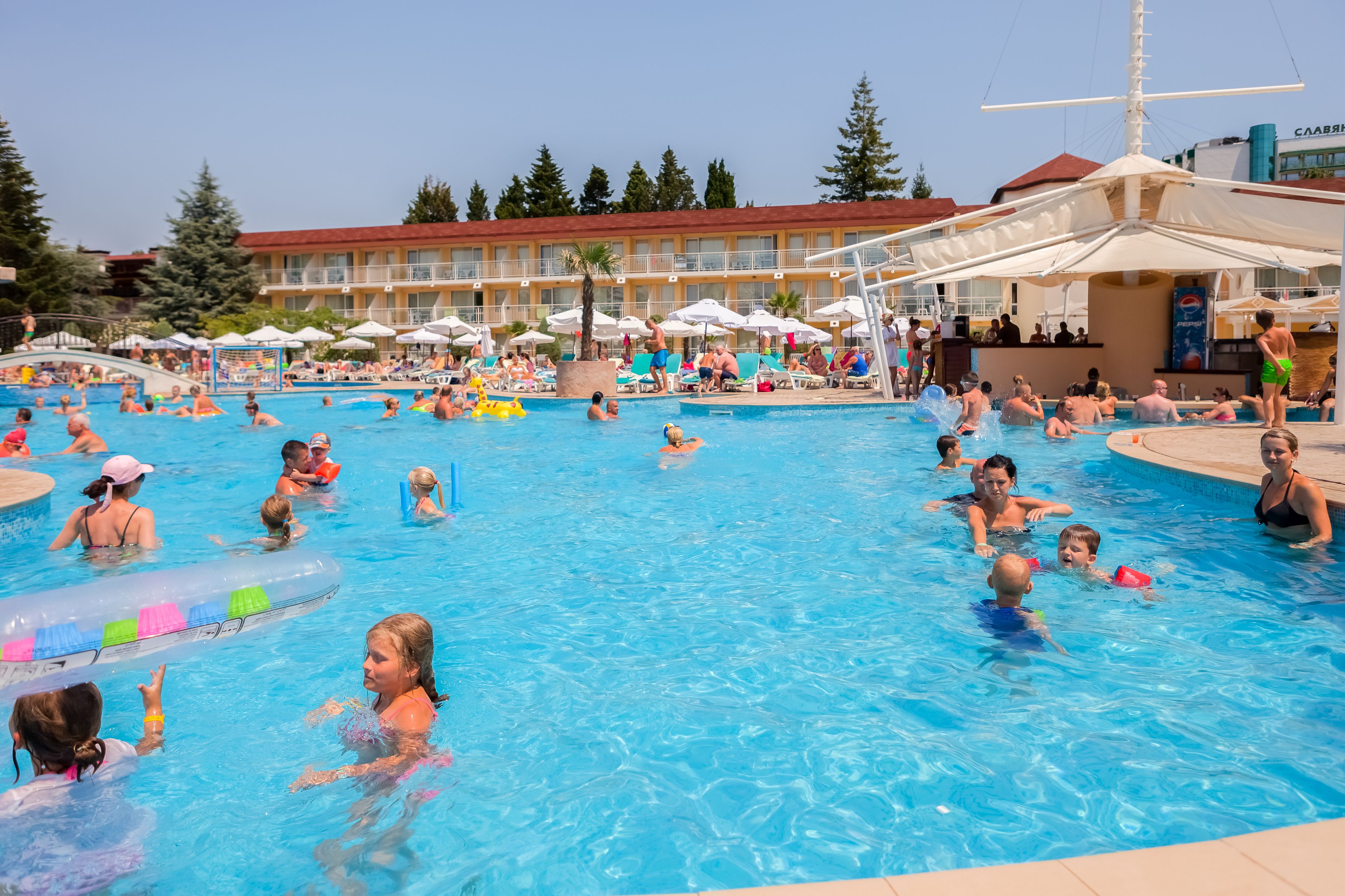 Un área de piscina con varias piscinas, sombrillas y sillas de descanso.