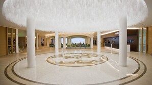 A spacious lobby with a central circular design, large white columns, and a reception area in the background. - DIT Evrika Beach Club Hotel (Nessebar)