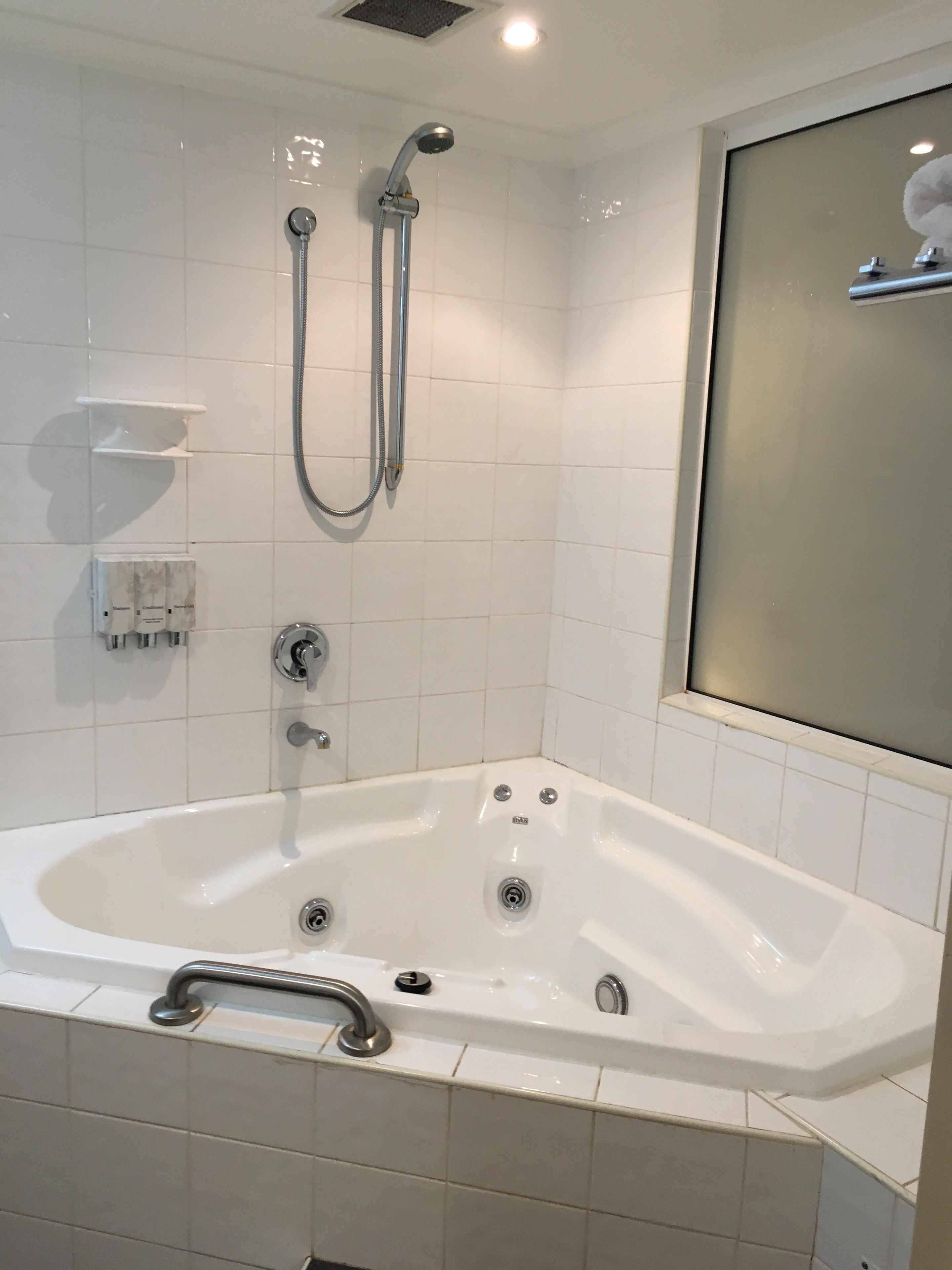 A modern bathroom with a freestanding bathtub, a handheld showerhead, and a wall-mounted faucet.