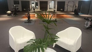 A gym with exercise equipment, white chairs, and a large plant. - The Select Inn Gosford (Wyoming)
