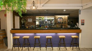 A bar area with wooden stools, a counter with bottles, and a hanging plant. - The Select Inn Gosford (Wyoming)