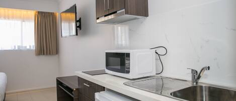 A compact kitchen with a microwave, a sink, and a compact refrigerator.