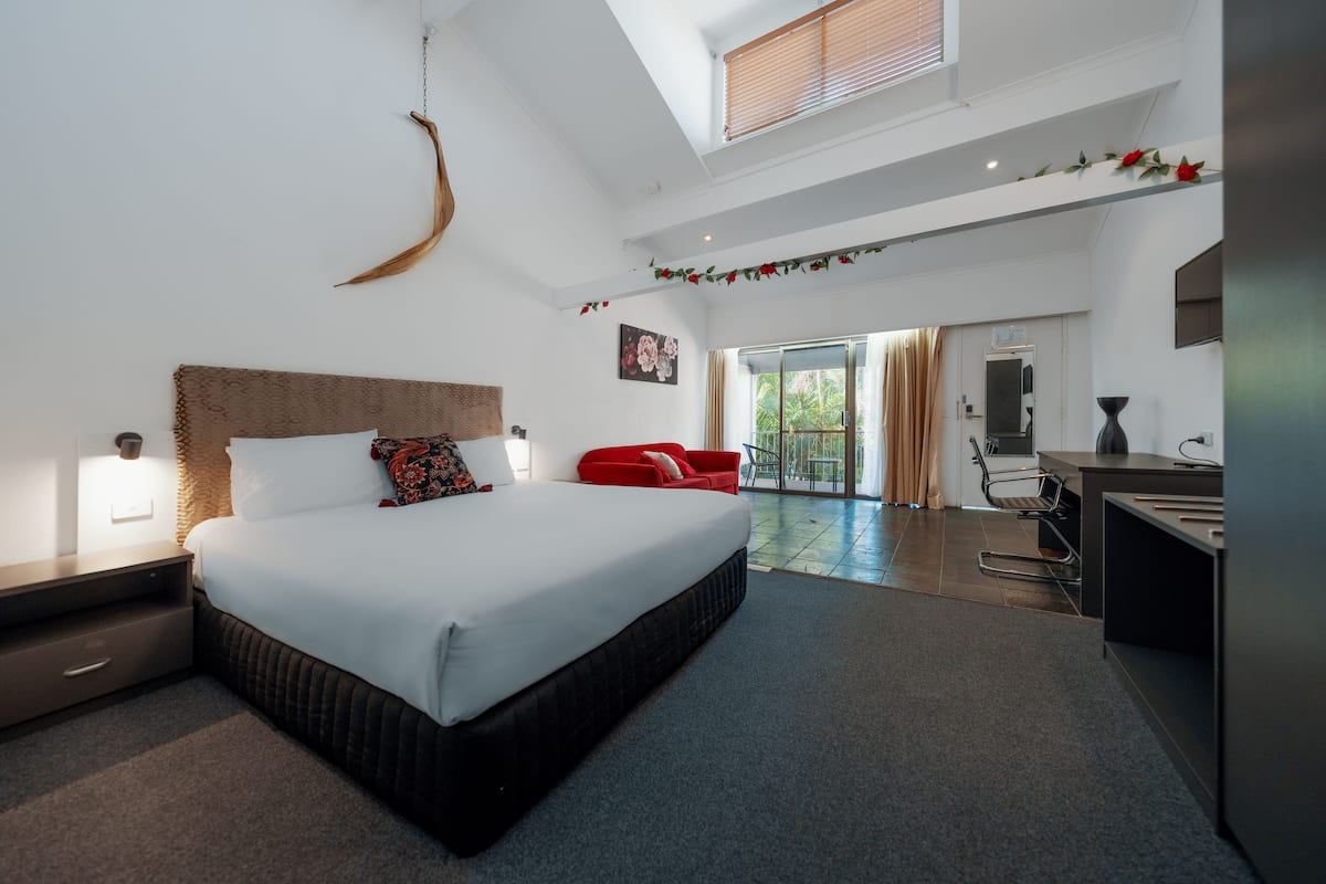 A modern hotel room with a large bed, a desk, and a view of the outdoors.
