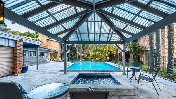 A covered outdoor swimming pool with a glass roof, a hot tub, and outdoor seating. - The Select Inn Gosford (Wyoming)