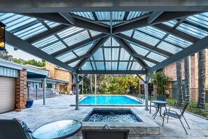 A covered outdoor swimming pool with a glass roof, a hot tub, and outdoor seating. - The Select Inn Gosford (Wyoming)