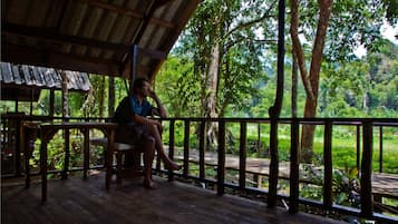 A wooden deck with a railing, a table, and a person sitting.