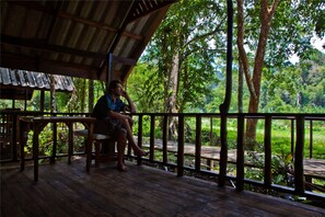 A wooden deck with a railing, a table, and a person sitting.