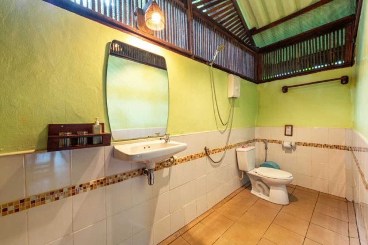 A bathroom with a sink, mirror, toilet, and shower.