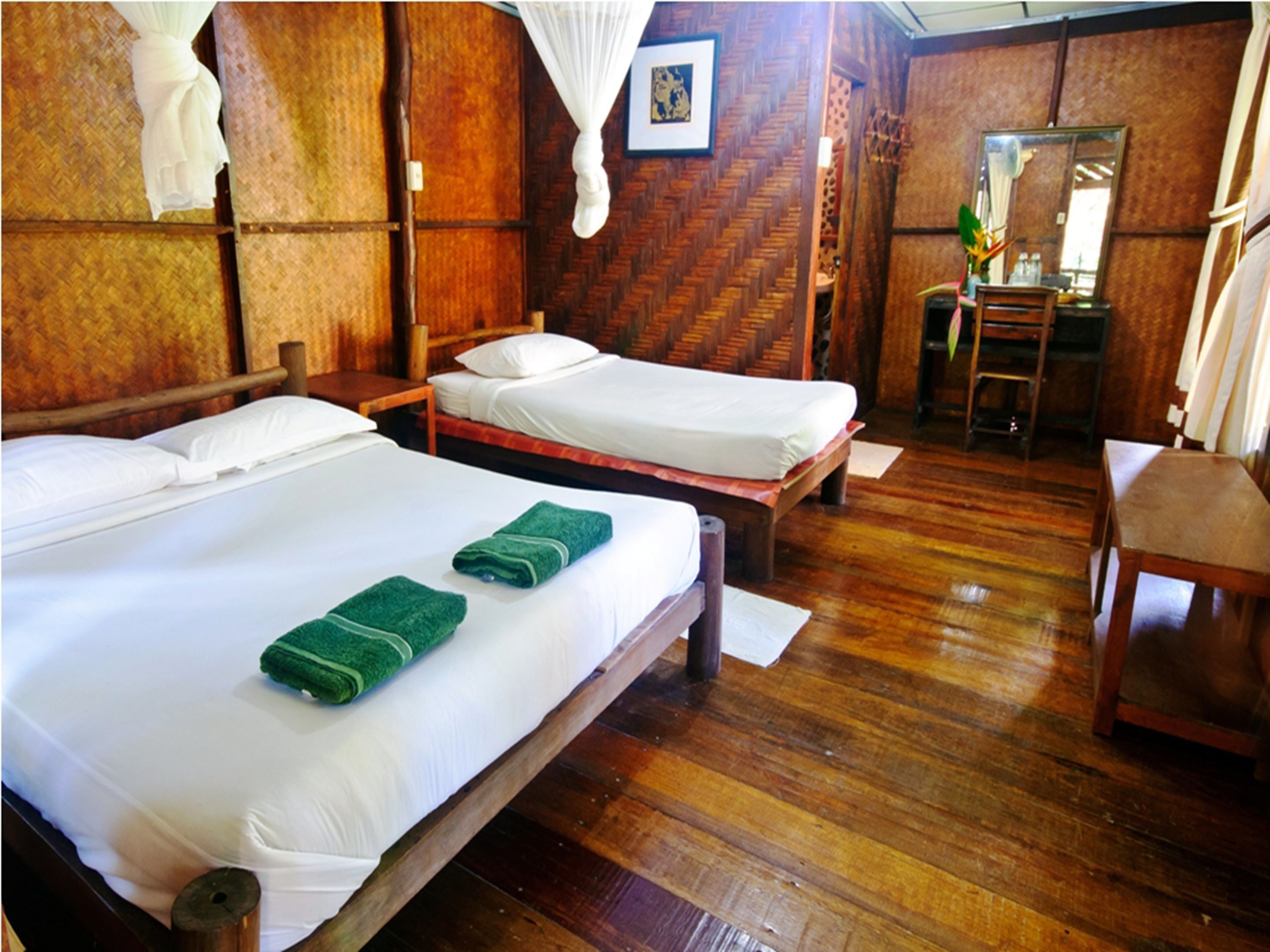 A room with two wooden beds, a wooden chair, and a wooden desk.