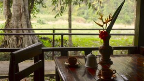 A wooden table with a teapot, a cup, and a vase with flowers.