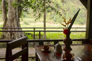 A wooden table with a teapot, a cup, and a vase with flowers.