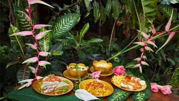 A table set with various dishes in a lush, green environment.