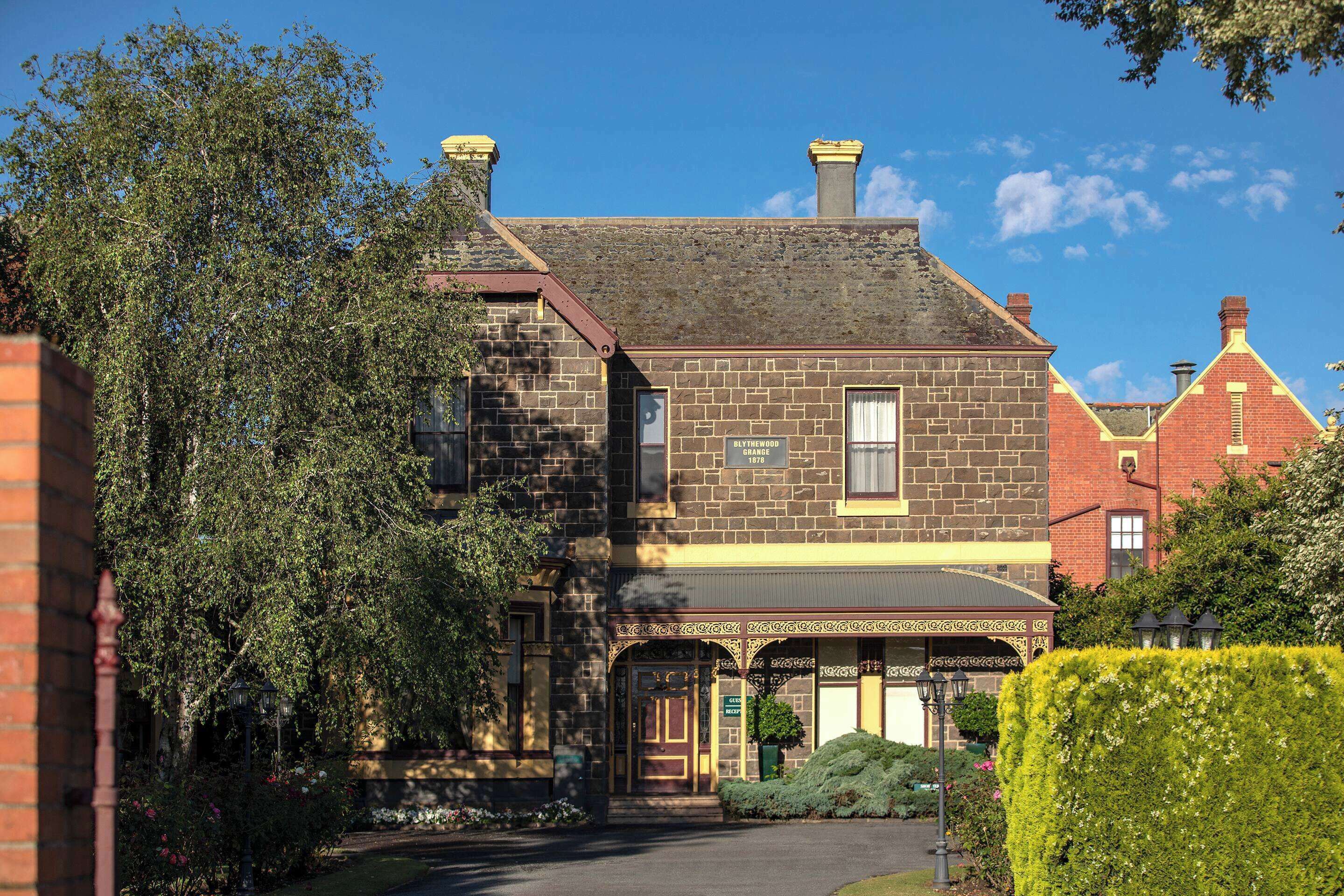 A historic building with a brick facade, a prominent entrance, and a well-maintained garden.