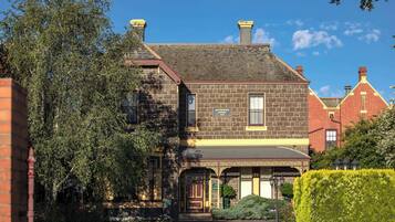 A historic building with a brick facade, a prominent entrance, and a well-maintained garden.