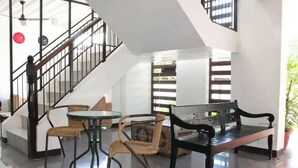 Eine geräumige Lobby mit Treppe, einer Bank und zwei Sesseln.