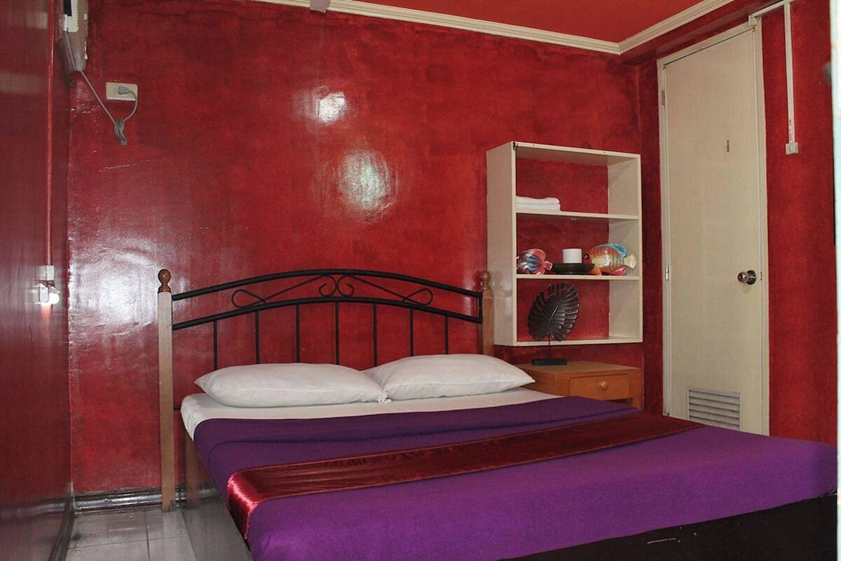A bedroom with a bed, a shelf with toiletries, and a wardrobe.