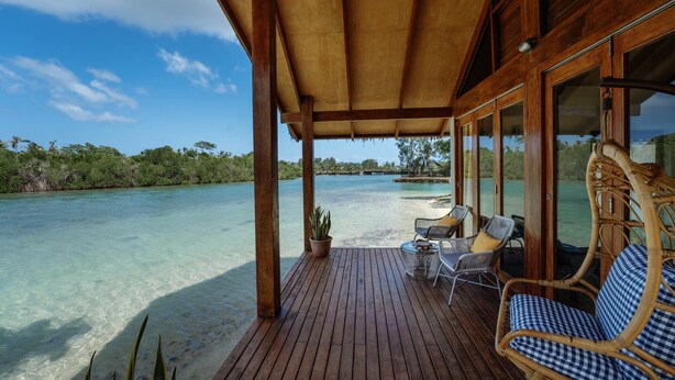 A wooden deck with outdoor seating, overlooking a clear blue sea and lush greenery. - MG Cocomo Resort Vanuatu (Port Vila)