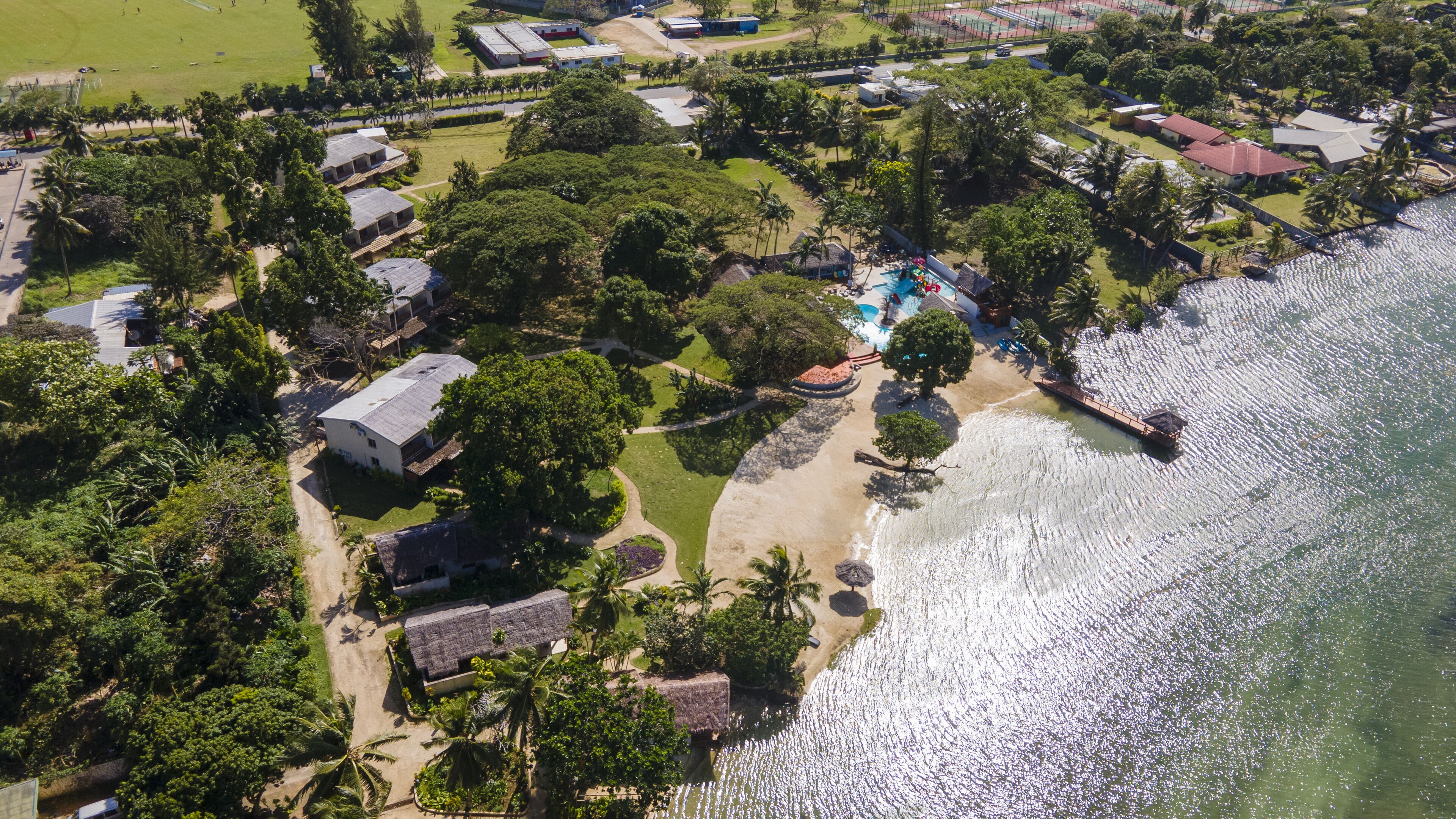 An aerial view of a coastal resort with multiple buildings, a beach, and a swimming pool.