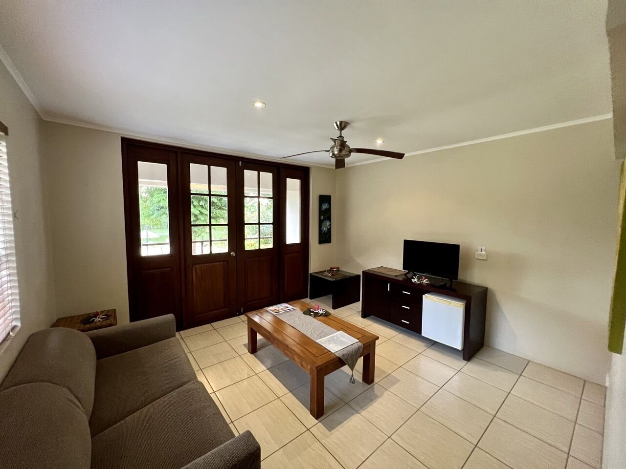 A living room with a sofa, a coffee table, a TV, and a ceiling fan.