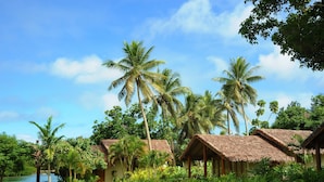 A resort with thatched-roof cottages, lush greenery, and a calm lake. - MG Cocomo Resort Vanuatu (Port Vila)