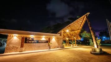 L'ingresso di un resort con facciata in pietra, un cartello che recita "M & Coconu Resort" e una struttura con tetto di paglia.