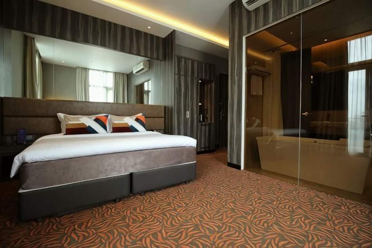 Une chambre d’hôtel avec un grand lit, une paroi en verre et une vue sur la ville.