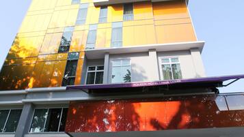 A multi-story hotel with a modern design, featuring a prominent yellow facade and a lower section with a red and orange exterior.