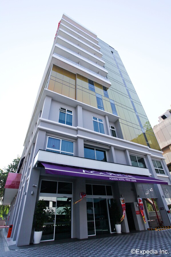 A modern hotel building with a glass facade, multiple floors, and a purple awning.