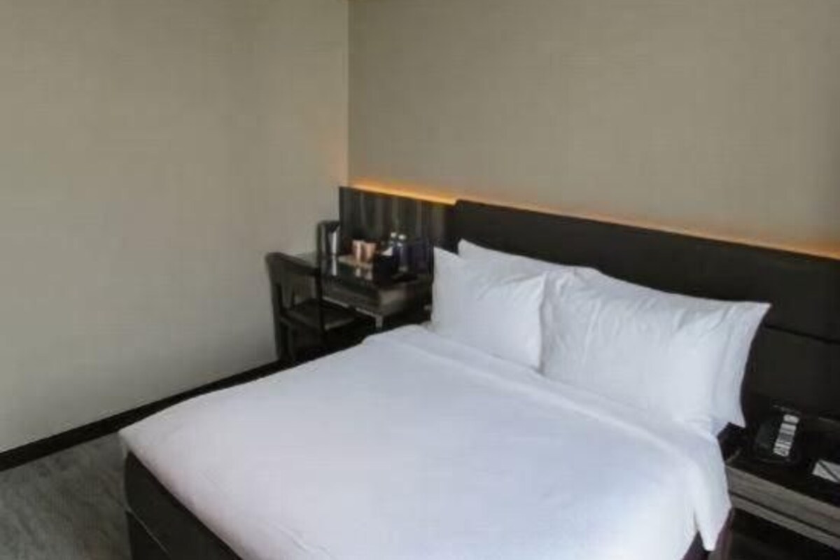 Una habitación de hotel con una cama, una mesita de noche, una lámpara y una silla.