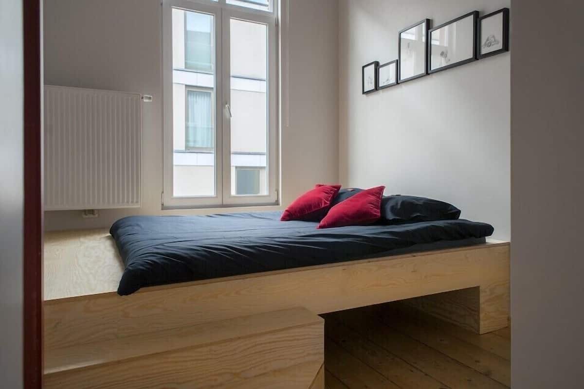 Un dormitorio pequeño y funcional con cama empotrada, ventana y radiador.