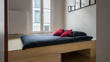 Un dormitorio pequeño y funcional con cama empotrada, ventana y radiador.