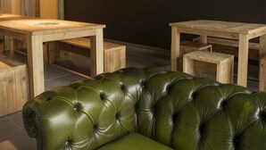Un sofá de cuero verde en una habitación con muebles de madera y suelo de baldosas.