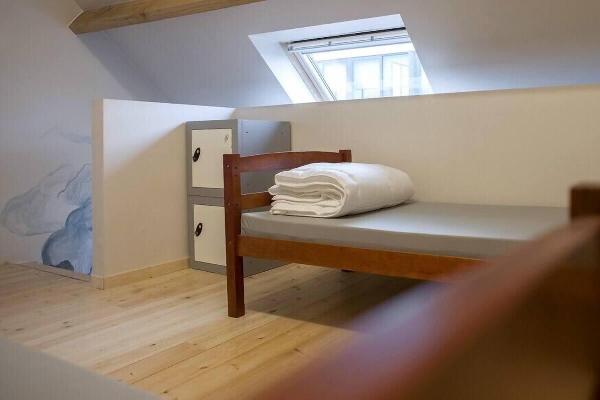 Una habitación pequeña y acogedora con una cama litera, un escritorio de madera y una ventana.