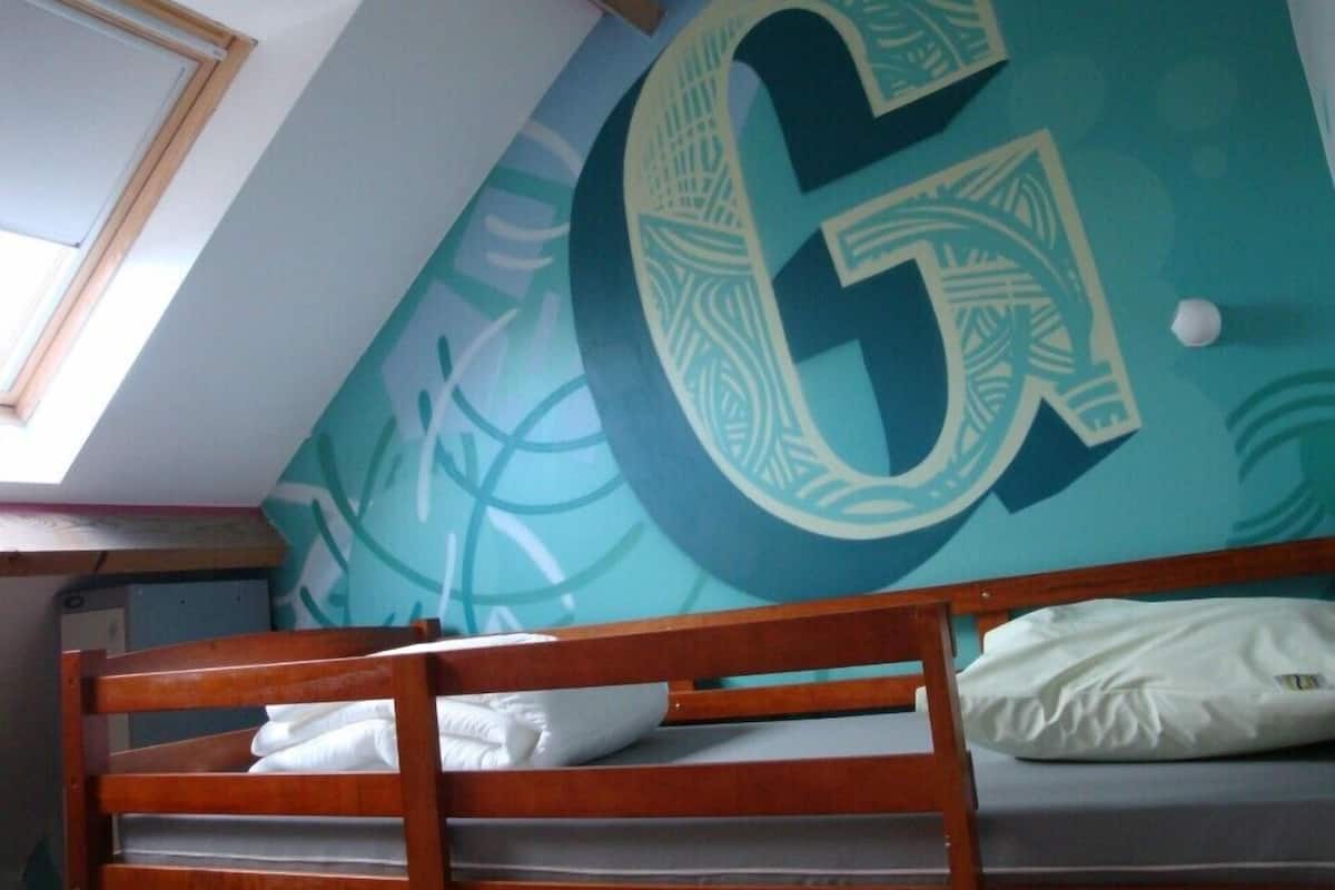 Una cama litera con un gran número 6 en la pared, un tragaluz y una pared lisa.