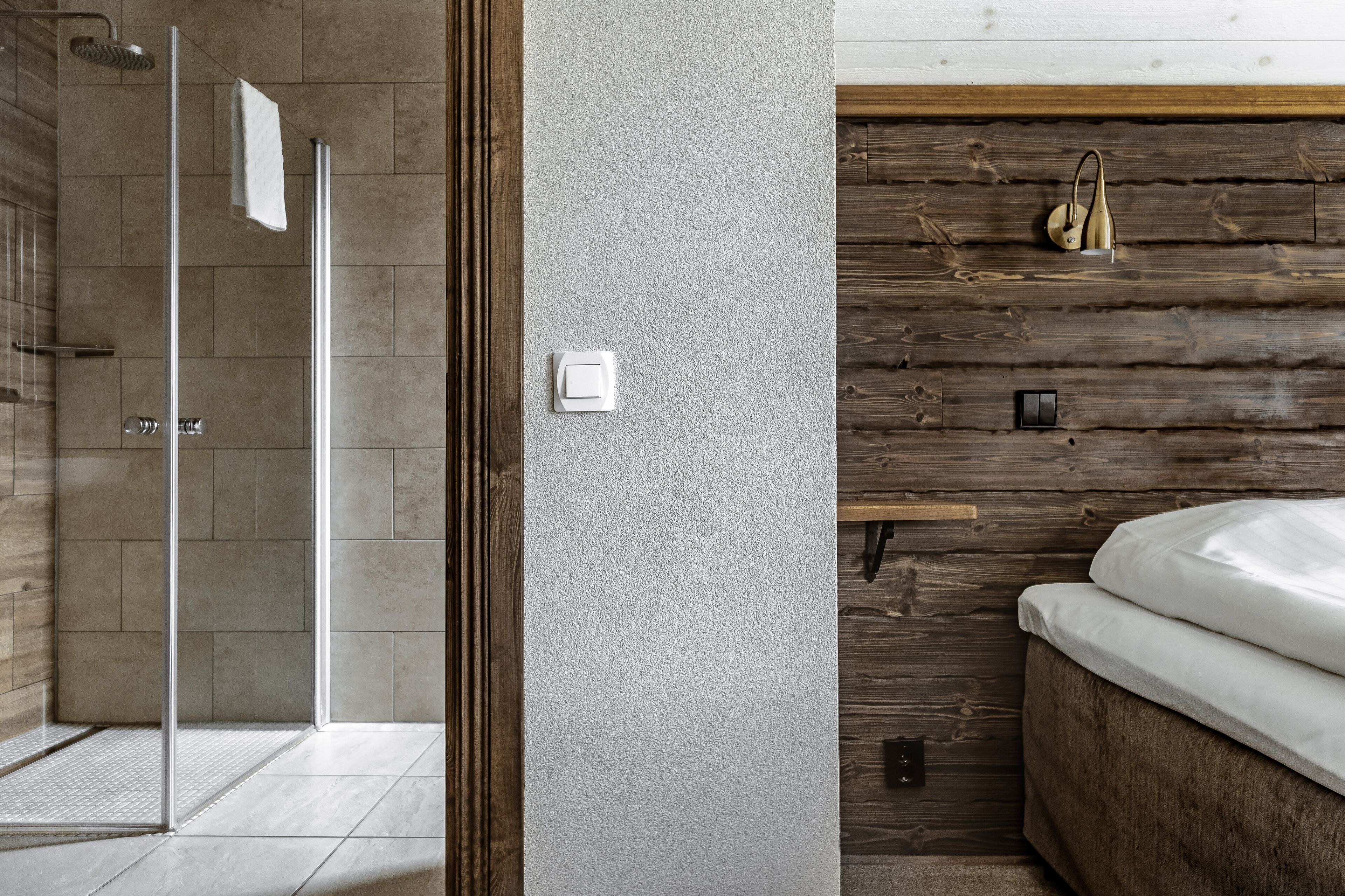 Une salle de bain moderne avec une douche à parois de verre, un mur en bois et un lit avec un matelas blanc.